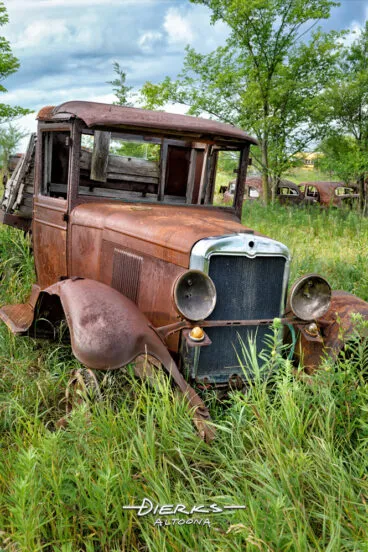 An old and rusty rum runner truck in junkyard high grass, Ford Model AA truck.
