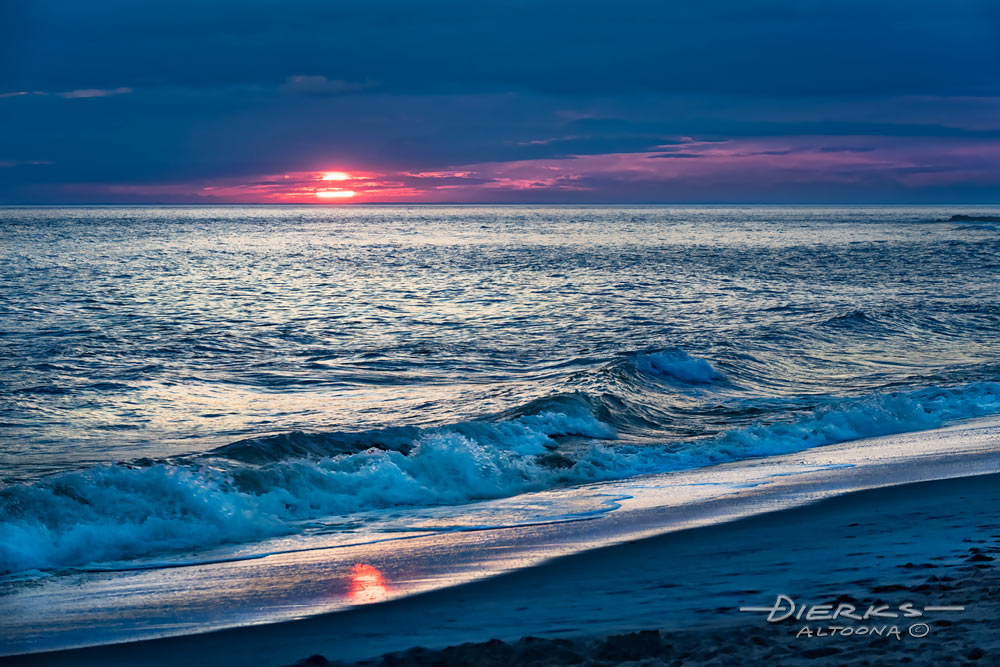 A winter sunset at the beach with the sun nearly down as the blue light rises in late evening. Cape May NJ.